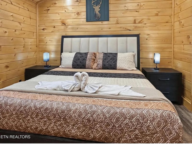 Rest in your cozy cabin bedroom with warm wood walls, plush bedding, and soft bedside lighting.