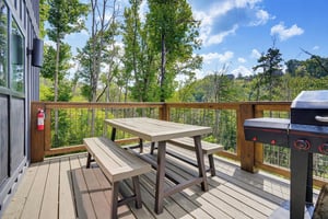 Your private deck invites alfresco dining with a picnic table, grill, and serene woodland views stretching into the distance.