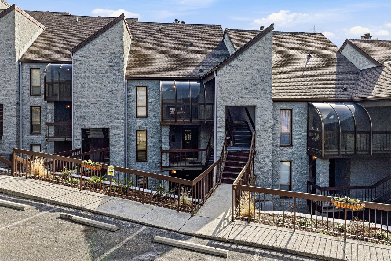 Modern stone property complex featuring distinctive curved glass balconies and contemporary architectural design in a wellmaintained residential setting.