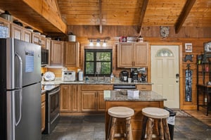 Step into your fully equipped cabin kitchen, where rich wood details and granite countertops set the stage for homecooked meals. The cozy space blends rustic charm with modern appliances, making it e