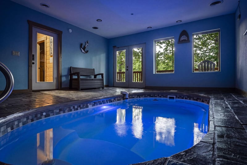 Dive into your private indoor pool sanctuary, where blue waters reflect the serene atmosphere and large windows frame peaceful garden views.