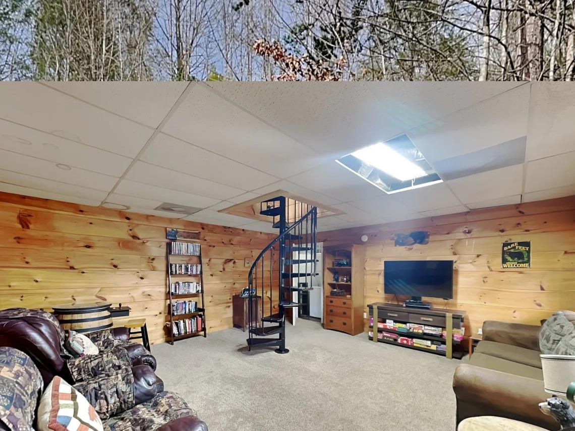 Unwind in your own private entertainment space with a cozy spiral staircase leading to a loft above, complete with TV, comfortable seating, and a skylight flooding the room with natural light.