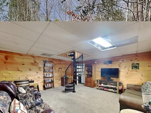 Unwind in your own private entertainment space with a cozy spiral staircase leading to a loft above, complete with TV, comfortable seating, and a skylight flooding the room with natural light.