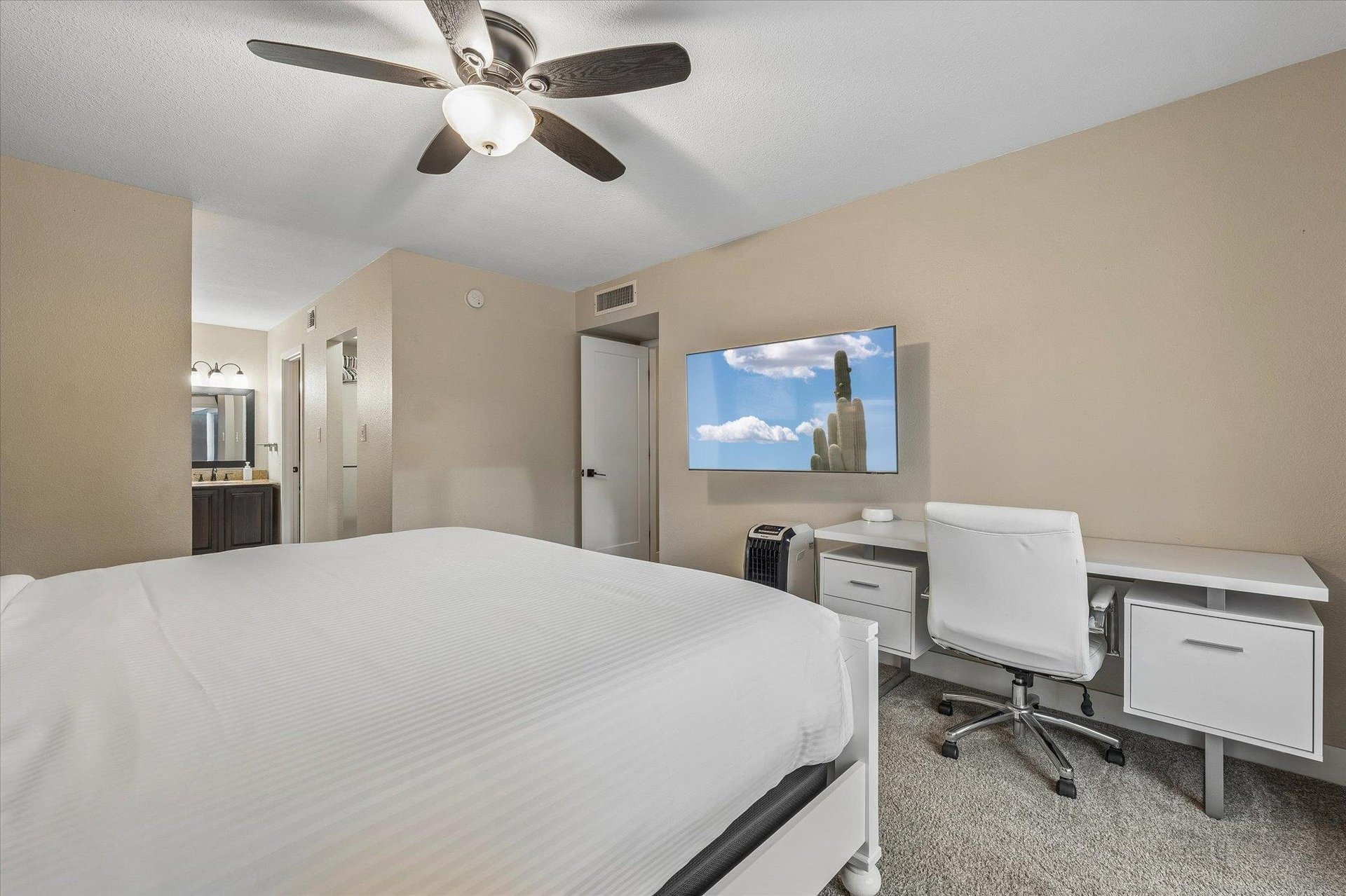 Desk space, flatscreen TV with streaming, and view of entry into en suite bathroom.