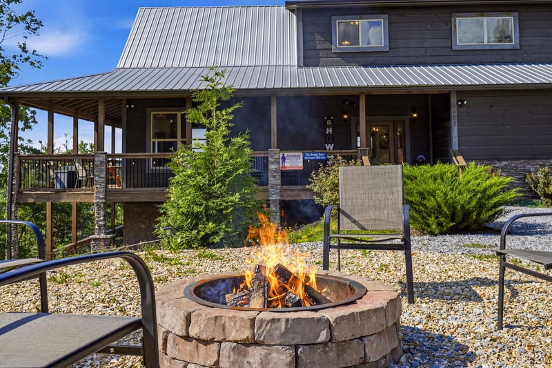 The stone fire pit provides a cozy gathering spot, with comfortable seating and the propertys welcoming exterior in the background.