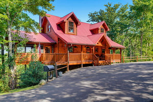 Nestled among lush green trees, this charming log cabin with its welcoming front porch and spacious parking area offers a peaceful mountain retreat.