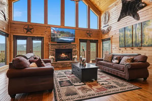 Sink into plush leather sofas in this lightfilled cabin, where soaring windows frame stunning mountain views and a crackling fireplace warms your cozy retreat.