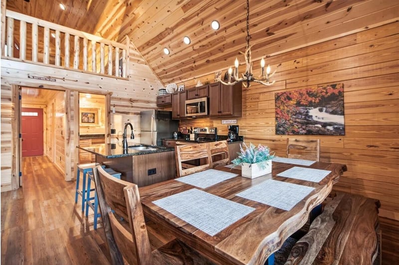 Step into your rustic mountain retreat featuring exposed wooden beams, a fully equipped kitchen, and handcrafted dining table perfect for family meals.