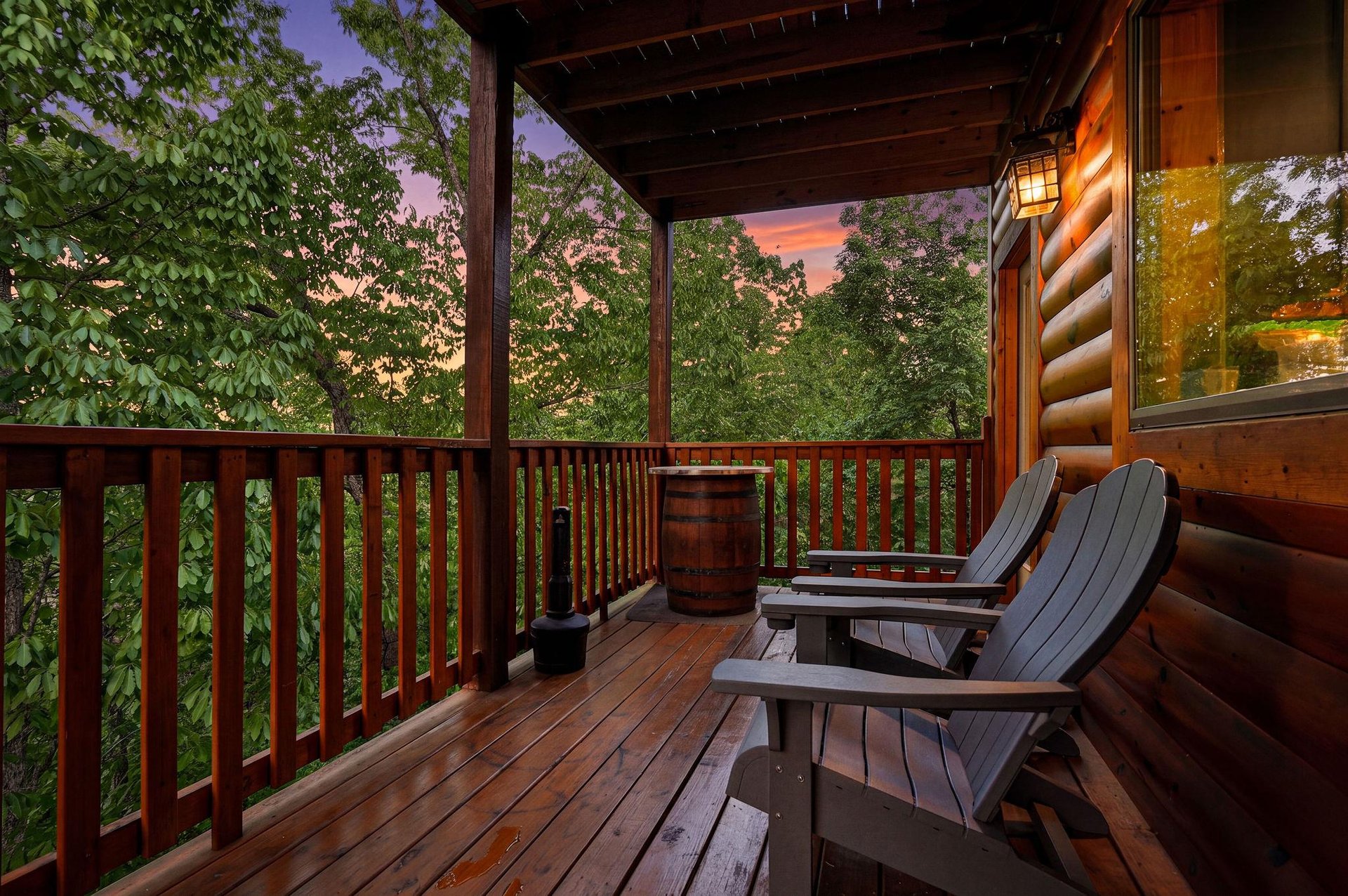 Step onto your private deck where Adirondack chairs await under a painted sunset sky, surrounded by lush forest canopy.