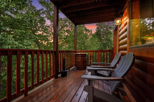 Step onto your private deck where Adirondack chairs await under a painted sunset sky, surrounded by lush forest canopy.