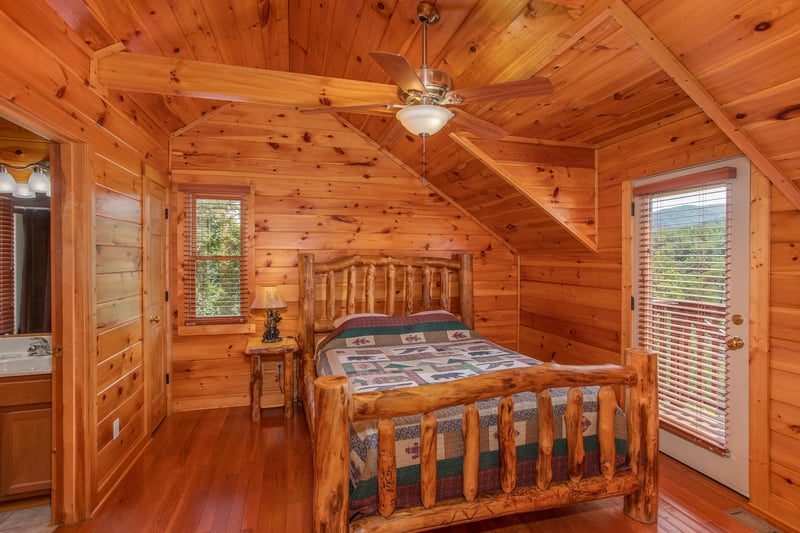 Queensized log bed in a bedroom with deck access at Four Seasons Lodge, a 3bedroom cabin rental located in Pigeon Forge
