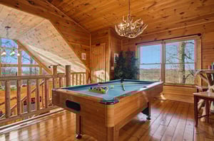 Your loft game room features rustic wood throughout, a fullsize pool table, and windows showcasing mountain views.