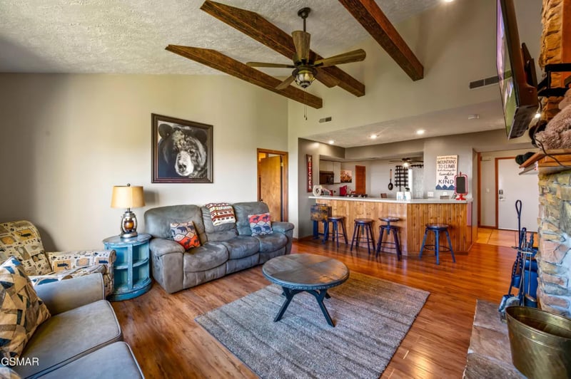 Relax in your spacious living area with exposed beams, cozy seating, and an open kitchen perfect for gathering.