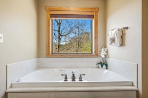 Soak in your private tub while gazing at mountain views through the rustic woodframed window—pure tranquility awaits.