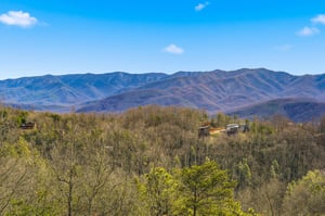 Stunning mountain vistas stretch across layered ridges beneath bright blue skies, showcasing the natural beauty surrounding this peaceful retreat.