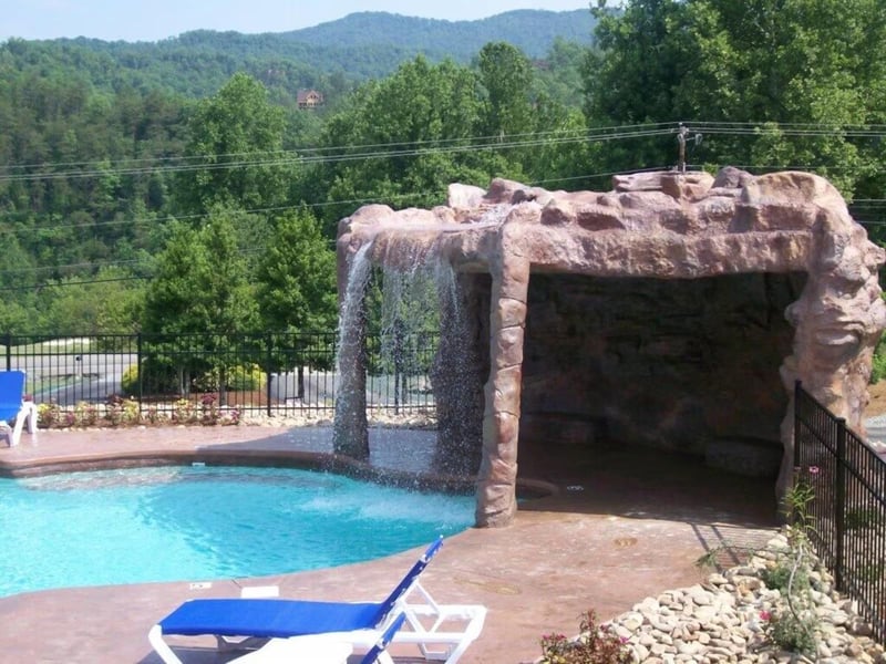 Dive into your private oasis with a stunning rock grotto waterfall cascading into crystalclear waters, surrounded by lush mountain views.