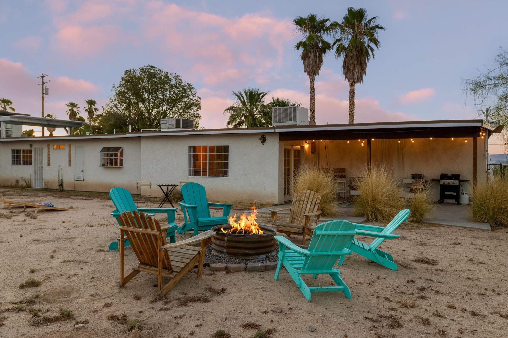 Spacious outdoor space with a covered patio, outdoor seating, firepit, hot tub, BBQ, and corn hole