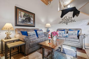 Relax in your rustic living room with cozy sofas, wildlifethemed decor, and warm mountain cabin charm perfect for unwinding.