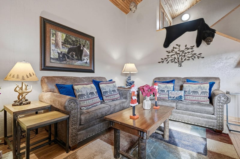 Relax in your rustic living room with cozy sofas, wildlifethemed decor, and warm mountain cabin charm perfect for unwinding.