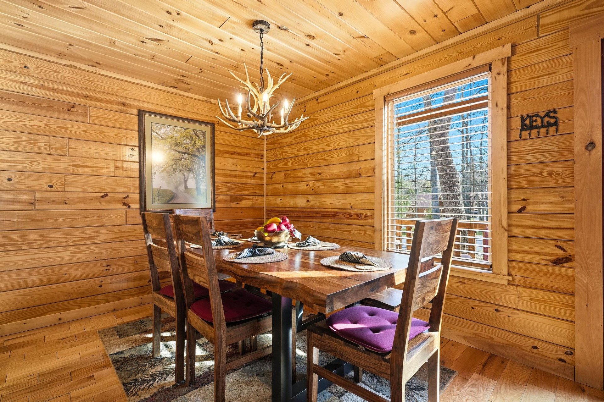 Gather around your rustic dining table beneath warm wood walls and antler chandelier for memorable meals together.