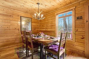 Gather around your rustic dining table beneath warm wood walls and antler chandelier for memorable meals together.