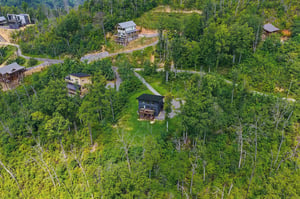 Aerial view of multiple vacation properties nestled among wooded hillsides, connected by winding private roads through the forest.