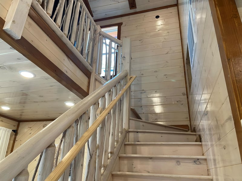 Ascend the handcrafted wooden staircase where rustic charm meets modern comfort, leading you to your cozy retreat above.