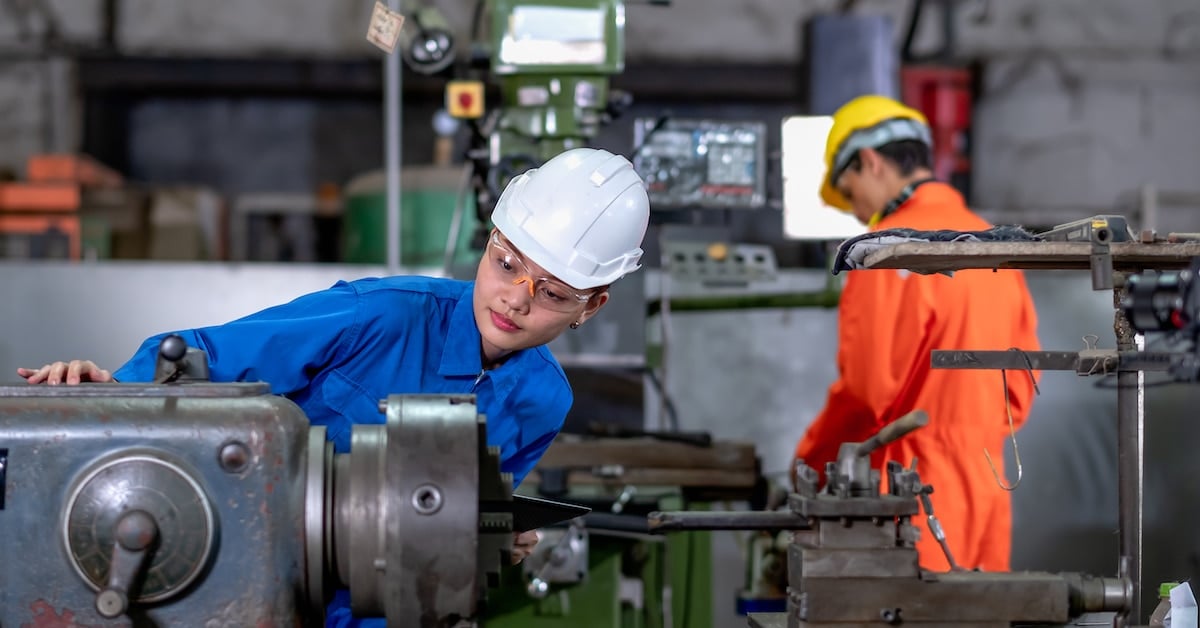 Asian factory worker woman looking at part of the machine