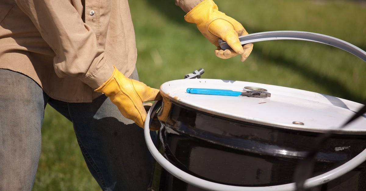 Utility worker with leather gloves opening or sealing a lubricant container