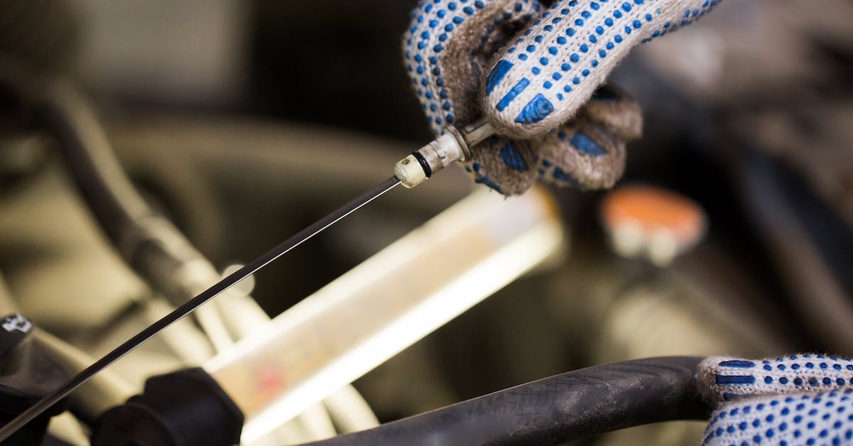 Mechanic checking motor oil level with dipstick