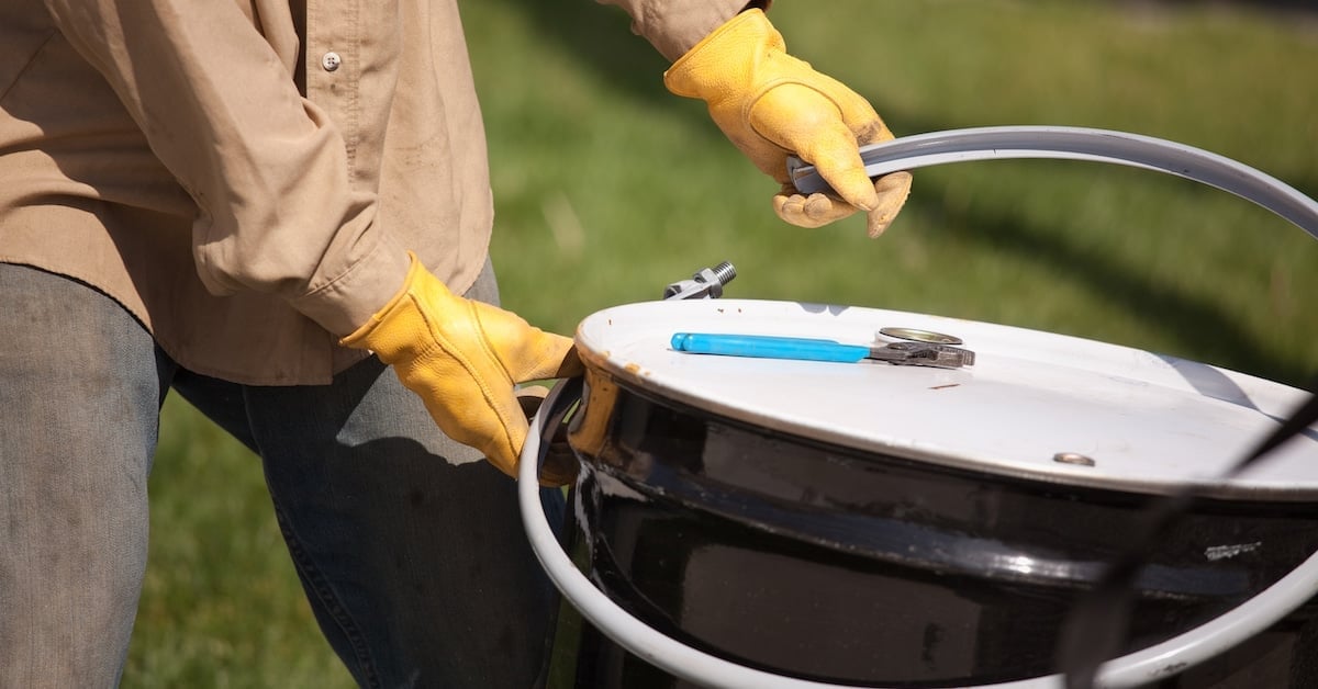 Utility worker with leather gloves opening or sealing lubricant container