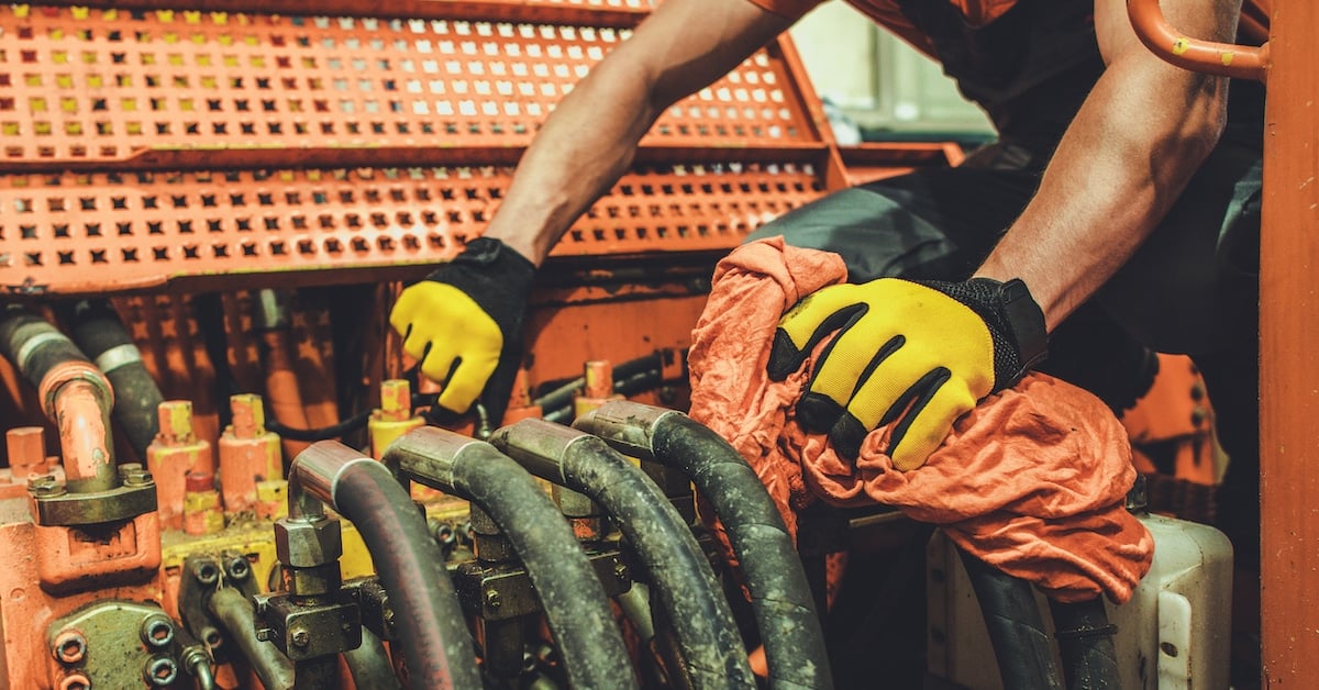 Heavy machinery mechanic performing pneumatic system lubrication