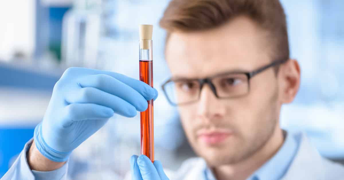 Man scientist in protective gloves holding test tube