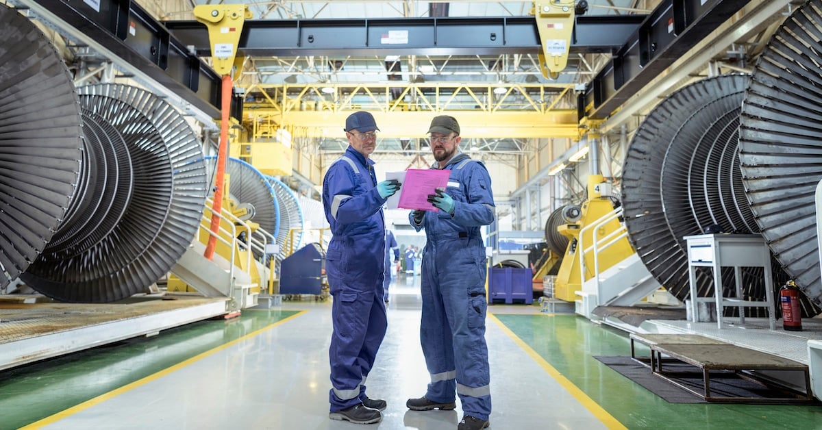 Engineers in discussion in turbine maintenance facility