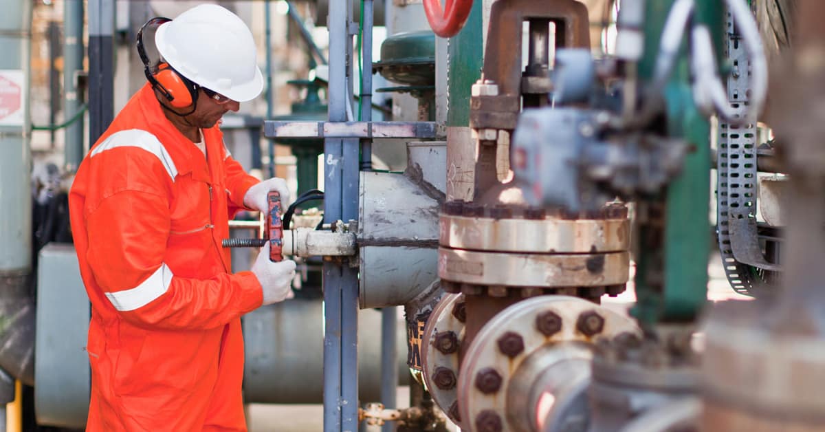 Worker adjusting gauge at oil refinery