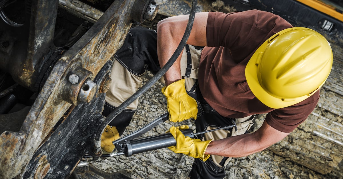 Industrial machinery technician with hand pump for manual lubrication