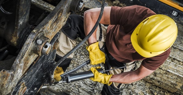 Industrial machinery technician with hand pump for manual lubrication