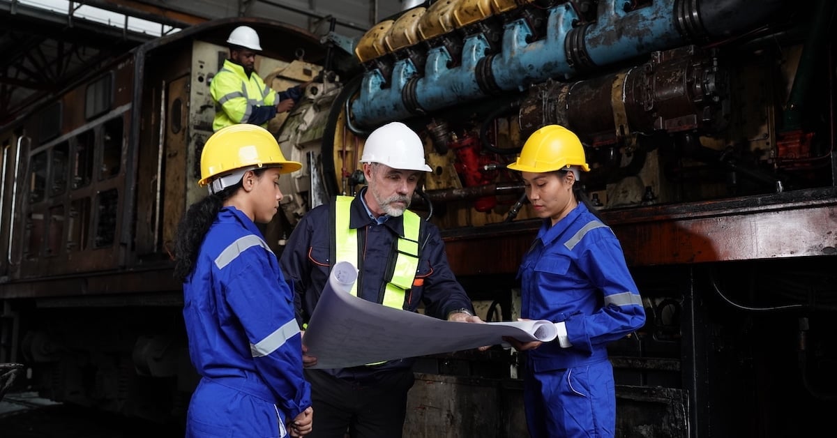 Engineer and apprentice in workshop reviewing lube oil system requirements