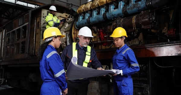 Engineer and apprentice in workshop reviewing lube oil system requirements