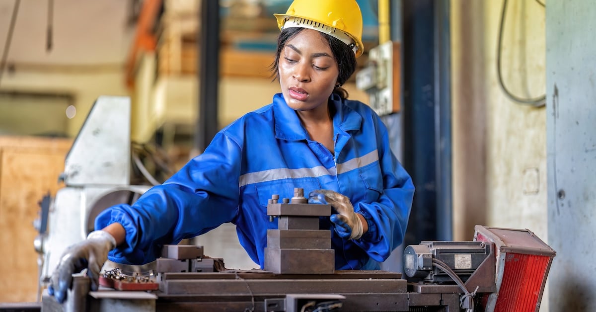 Woman worker in uniform operating machine at factory