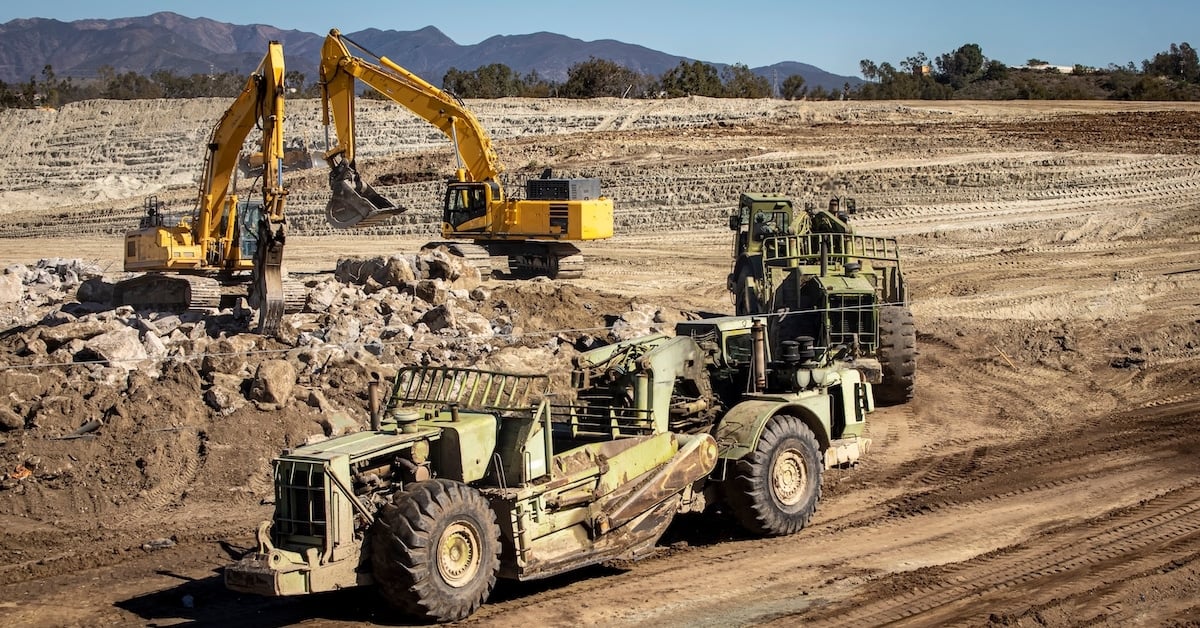 Heavy equipment graders and bucket cranes on a construction site