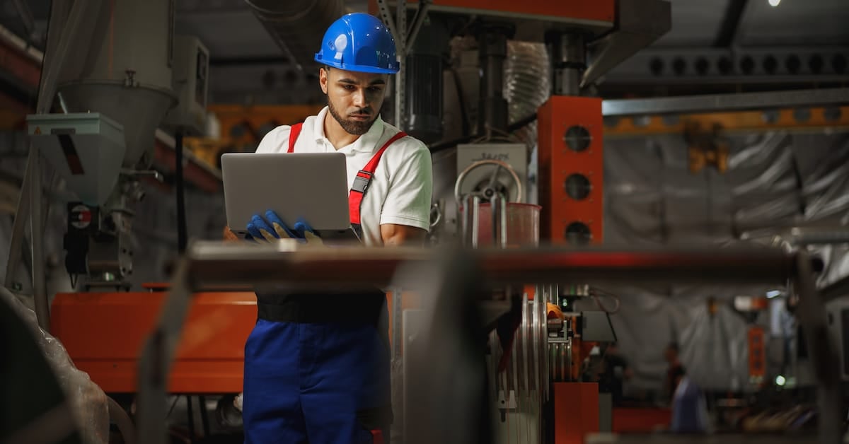 Industrial worker with laptop working in a cable plant