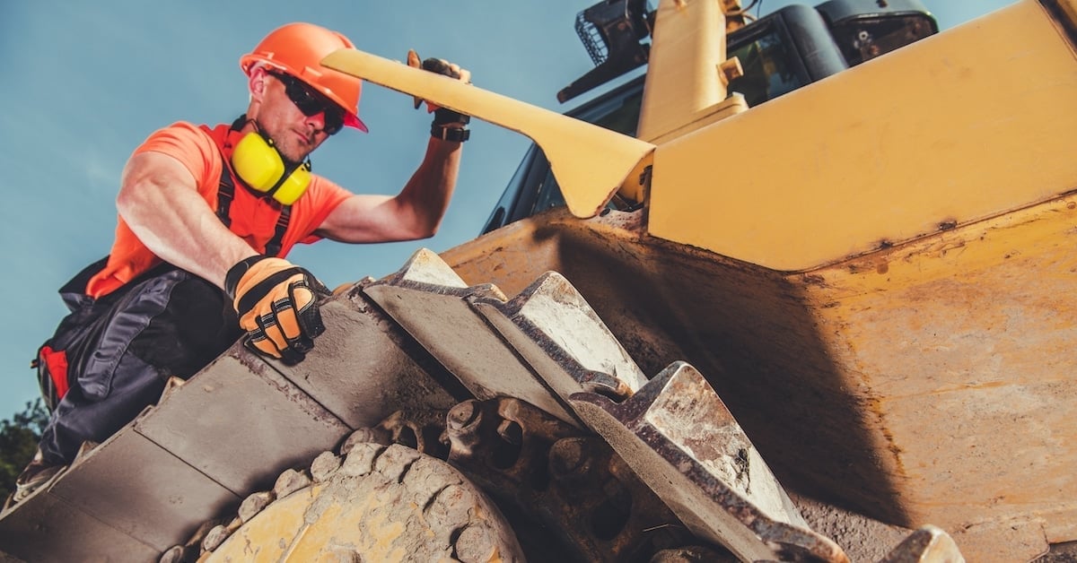 Heavy equipment mechanic performing condition-based monitoring for lubrication