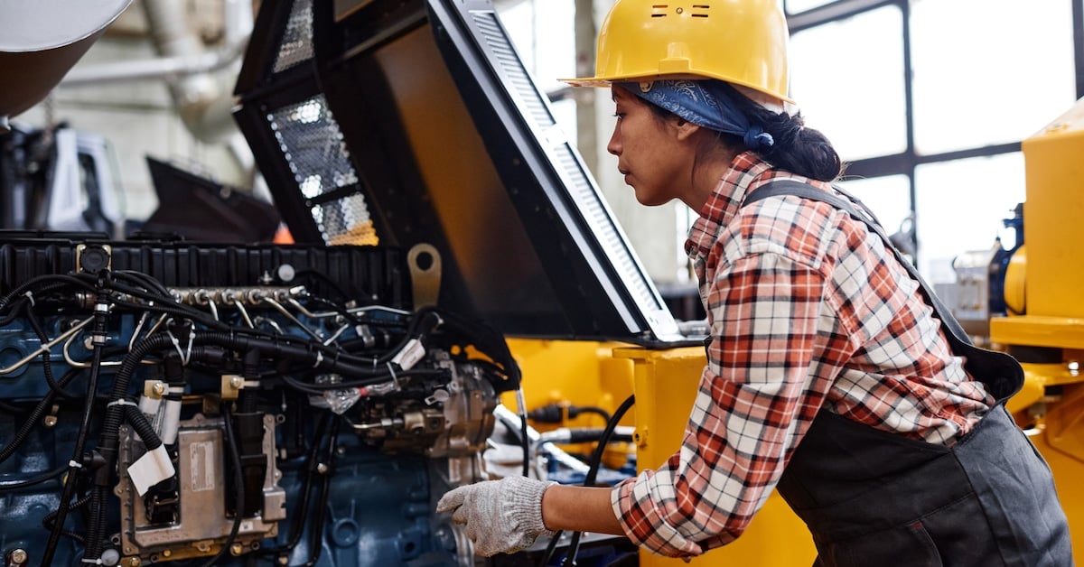 Young female technician in coveralls and hardhat