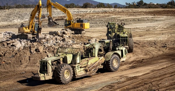 Heavy equipment graders and bucket cranes on a construction site