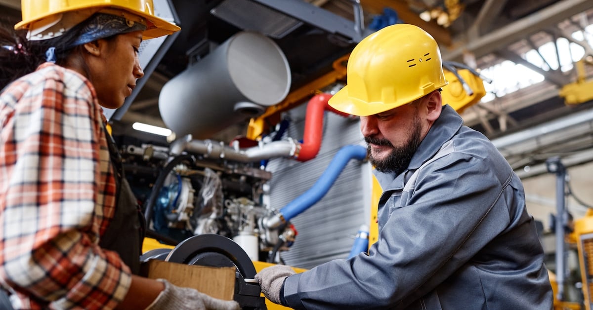 Mature workman in hardhat and workwear fixing shaft