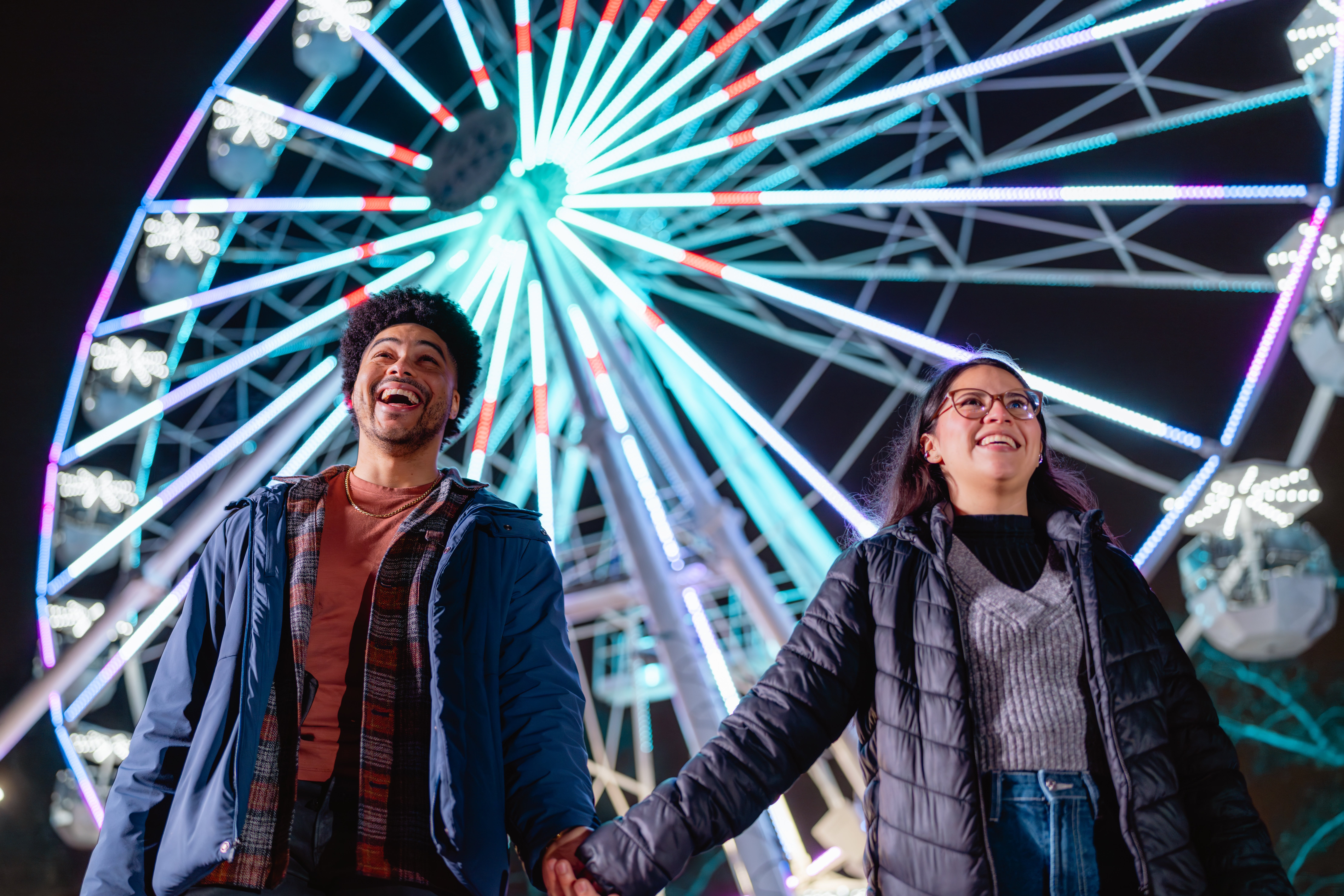 A smiling couple stands in front of the new ferris wheel installed at Philadelphia Zoo.