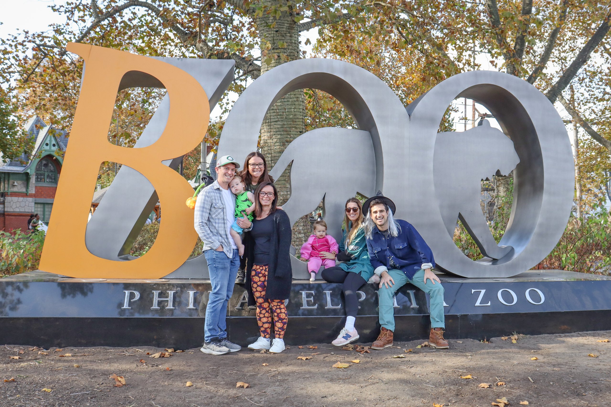 Two families pose for a photo in front of the Boo at the Zoo sign at Philadelphia Zoo.