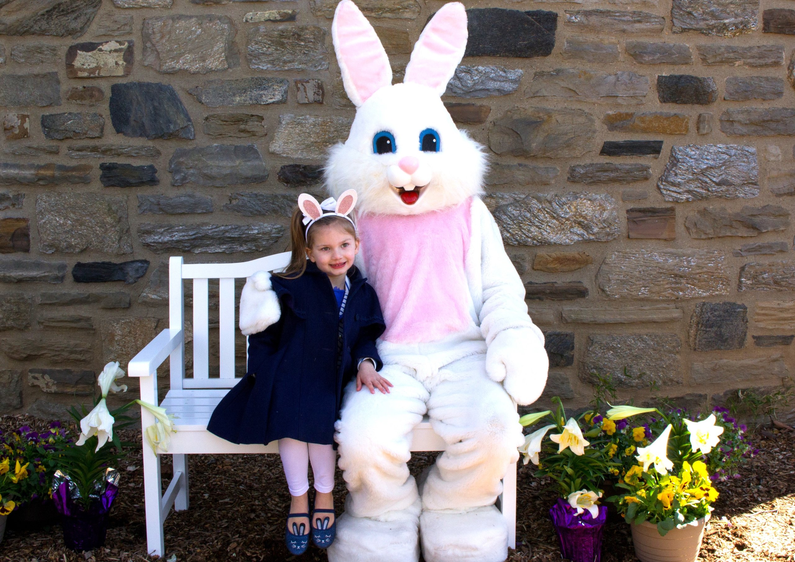 A child sits on a bench for a photo with the Easter bunny at Philadelphia Zoo.