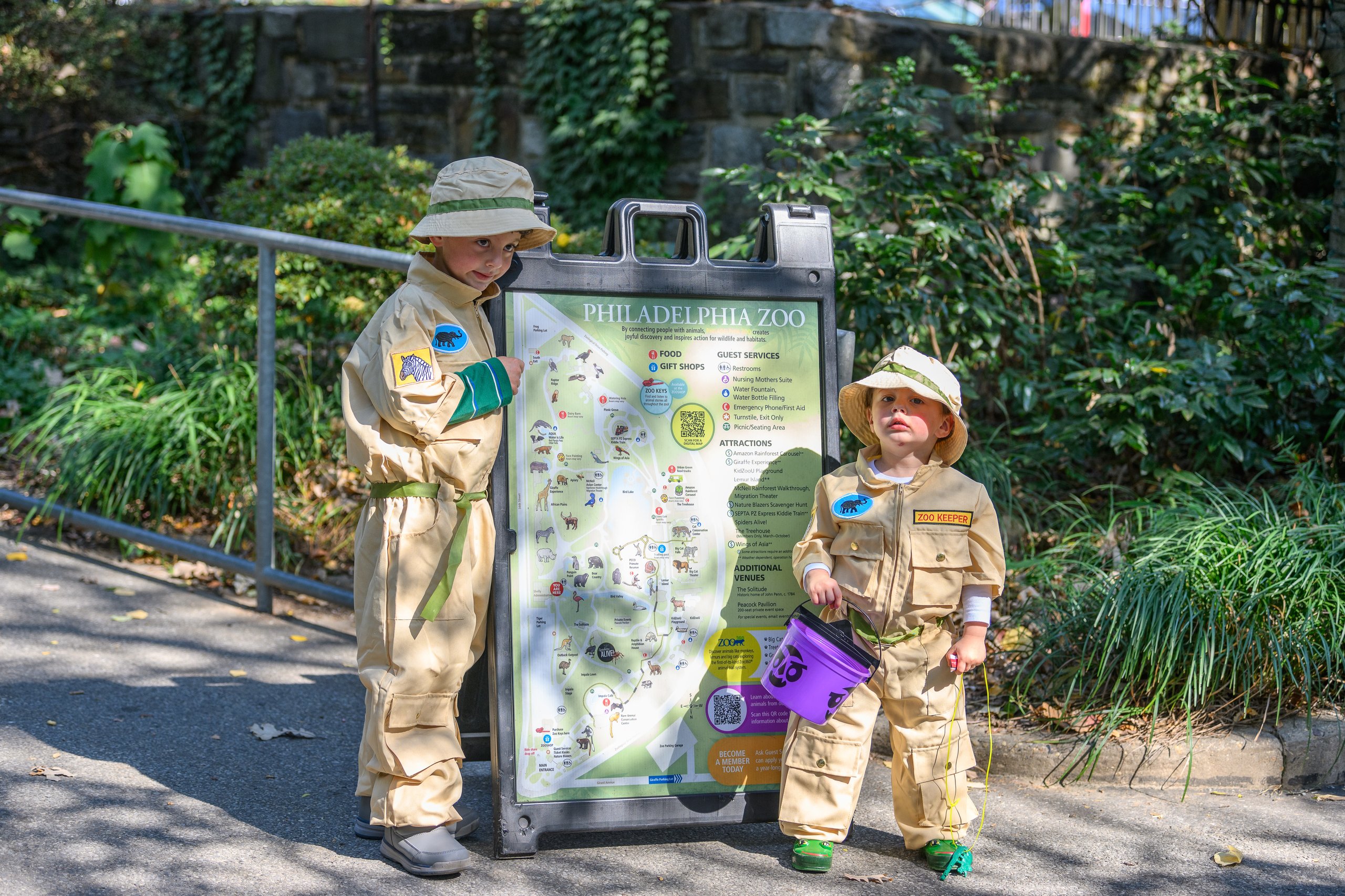 Two small children in Ghostbusters costumes pose next to a zoo sign during Boo at the Zoo.